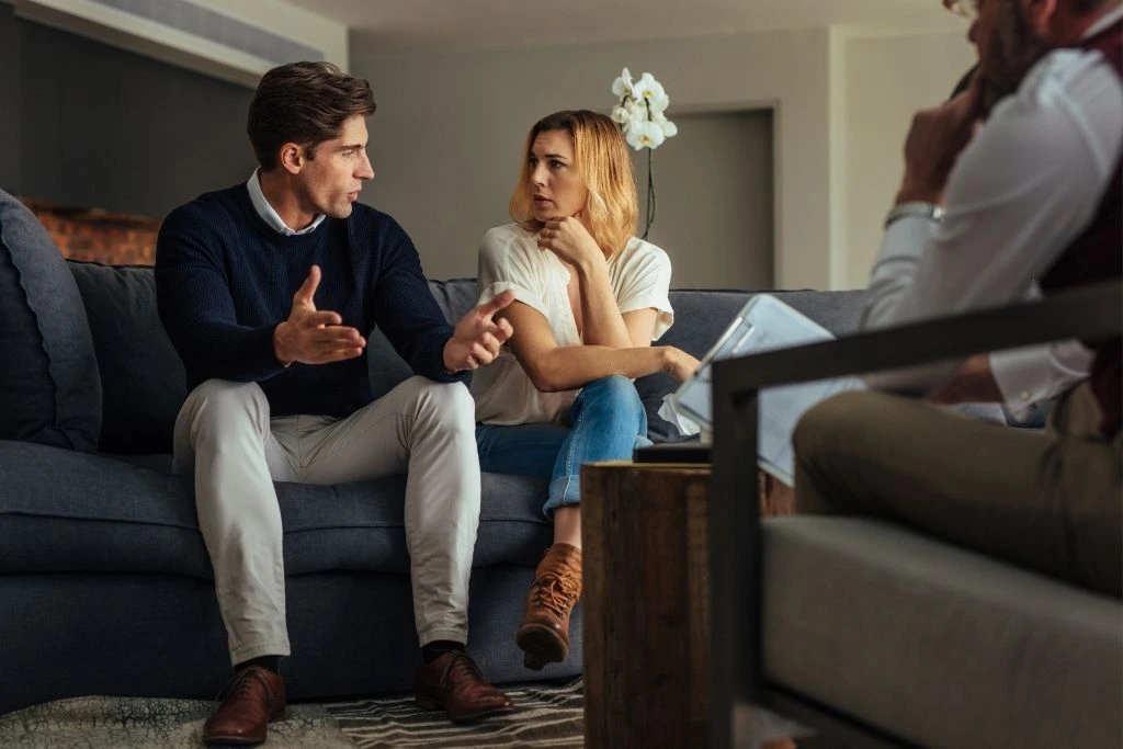 A couple on a couch in a serious discussion with  Clamon Counseling